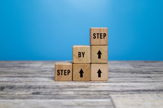 step by step word on wooden blocks staircase isolated on blue background. concept of success progress or career
