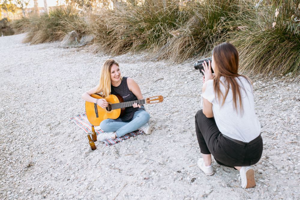 Young woman shooting friend playing guitar