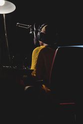 Unrecognizable Black woman in headset in dark broadcast studio
