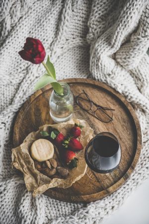 Wine, snacks and glasses on tray with with one flower, top view