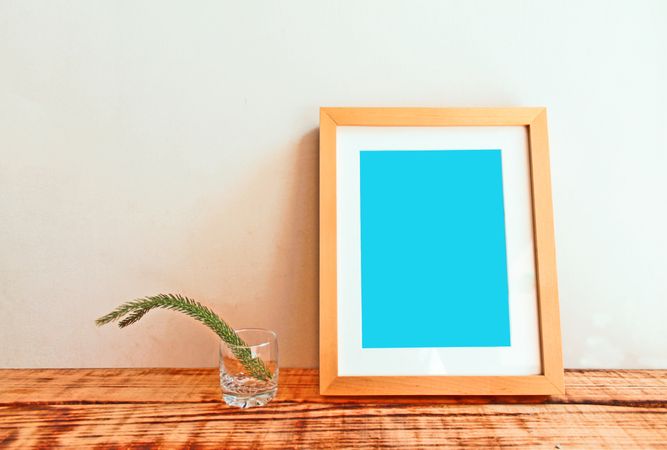 Wooden picture frame on desk with branch mockup