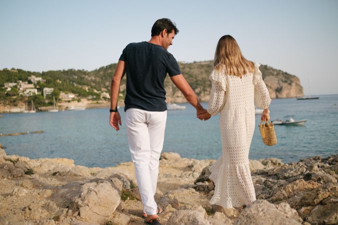 Couple walking on rocky seashore