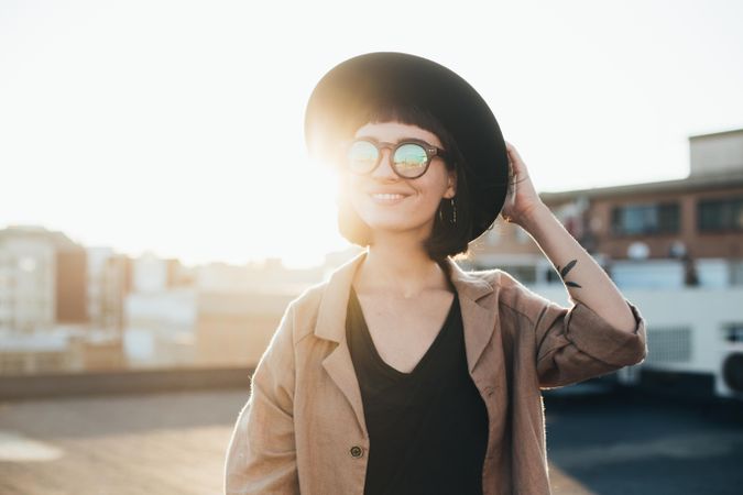 Backlit woman smiling in sunglasses outside at sunset