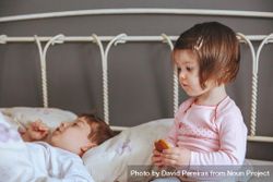 Closeup of thoughtful little girl holding cookie sitting in bed with brother on a relaxed morning bxWkj4