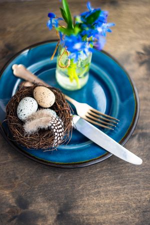 Spring table setting with lush scilla flowers on plate with nest and eggs