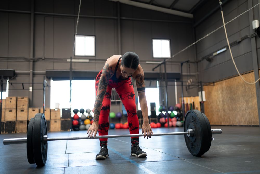 Woman reaching down to barbell in gym