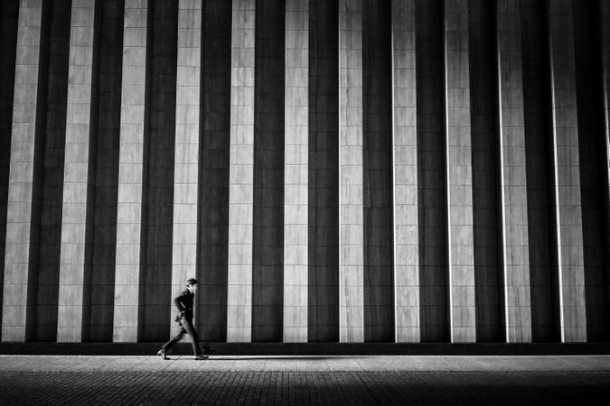 Grayscale photo of person walking on sidewalk