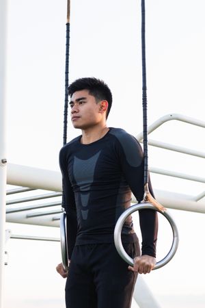 Athletic man practicing sport on gymnastic rings