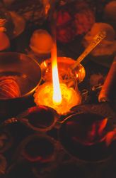 Lit diya beside saffron flowers on a table