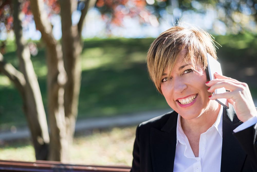 Smiling businesswoman talking on cellphone in park