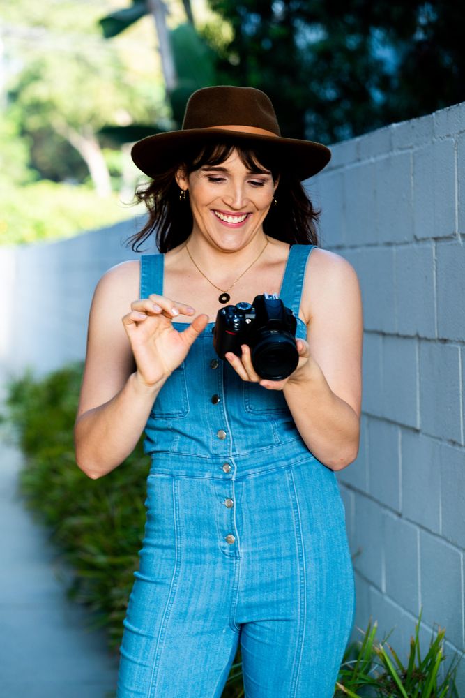 Smiling female photographer looking down at camera during shoot
