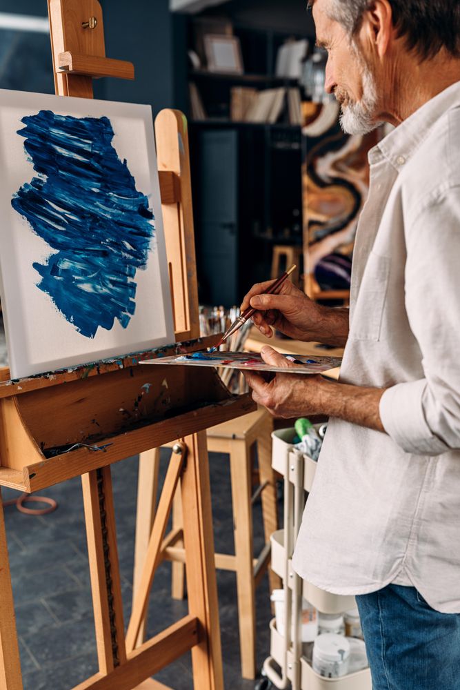 Man with grey beard painting in art studio