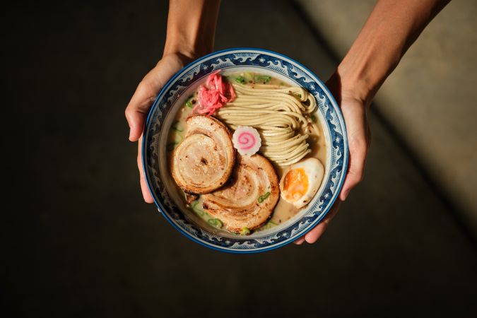 Crop female with bowl of ramen in hands