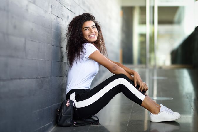 Smiling female in leggings sitting outside of building entrance