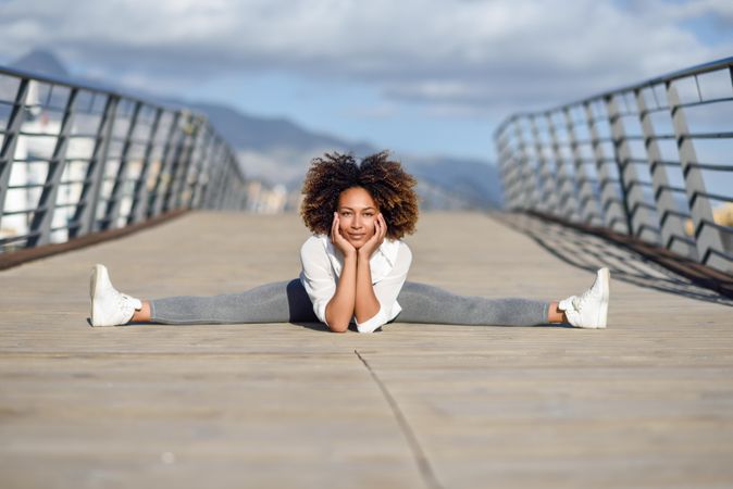 Woman leaning down into side splits on bridge with head resting on hands