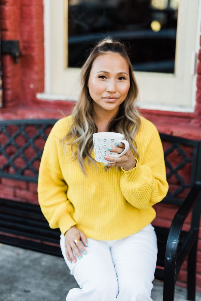 Woman in yellow long-sleeved shirt holding ceramic mug