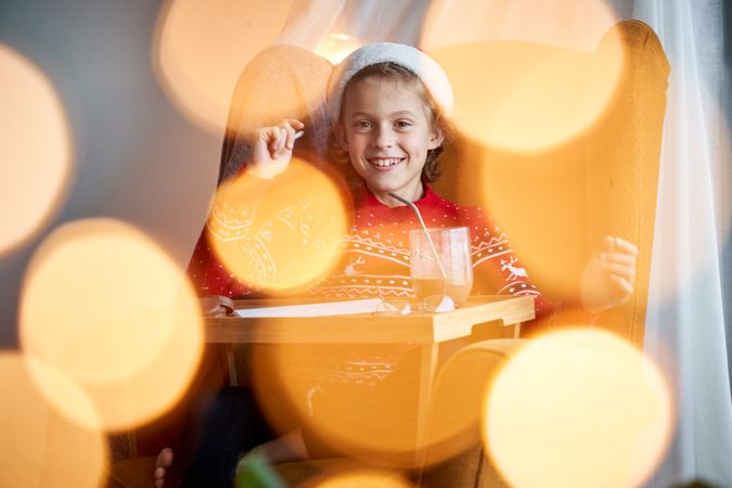Smiling boy in Santa hat writing letter