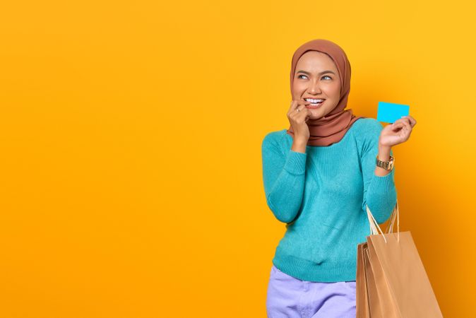 Muslim woman with shopping bags feeling tempted by credit card