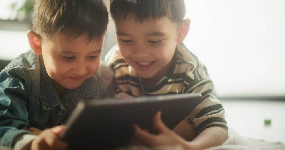 Portrait of Two Male Asian Kids Using a Digital Tablet During Weekend in their Room.