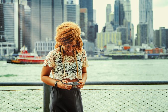 Happy Black woman photographer checking photos she took of Manhattan skyscrapers