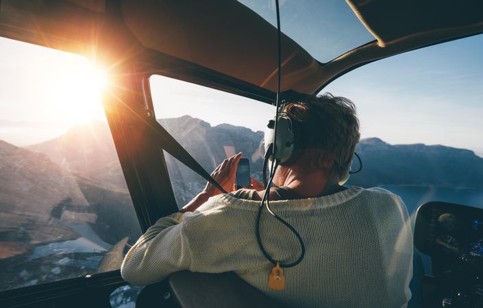 Woman sitting in helicopter taking photos while in flight