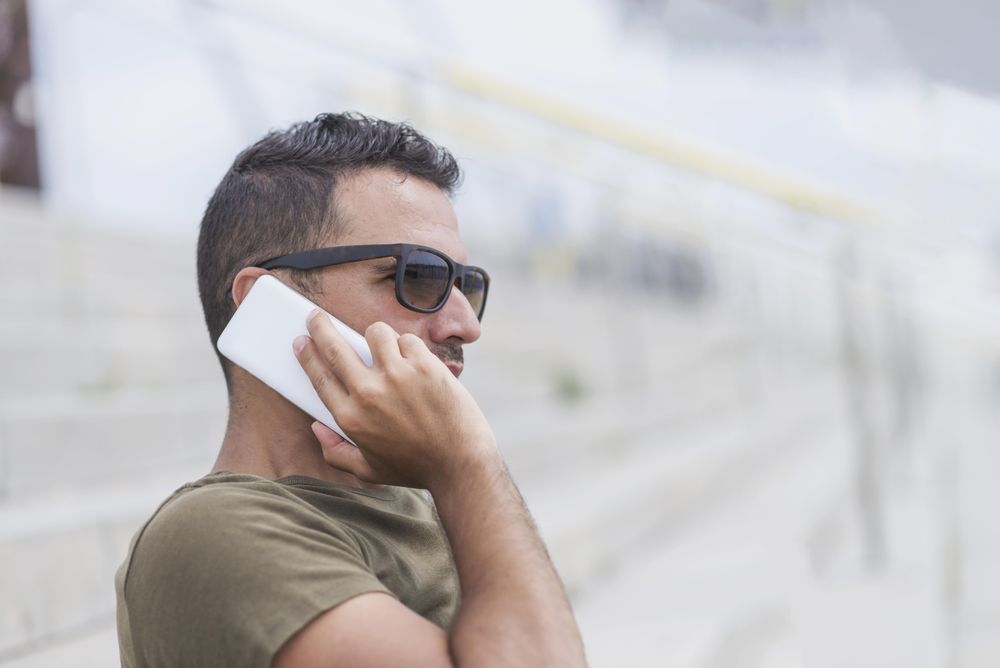 Side view portrait of male sitting on stairs talking on cellphone
