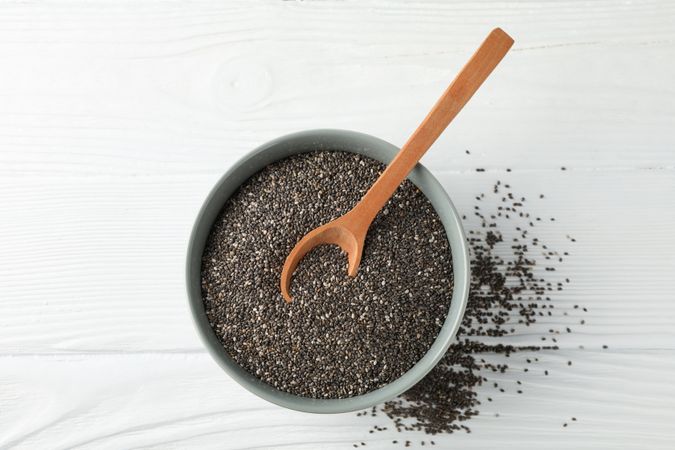 Chia seeds, wood spoon and bowl on wooden background, copy space