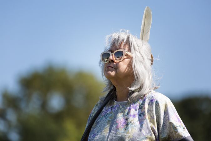 Red Wing, MN, USA - September 22nd, 2017: Mature Sioux woman with modern sunglasses and feather