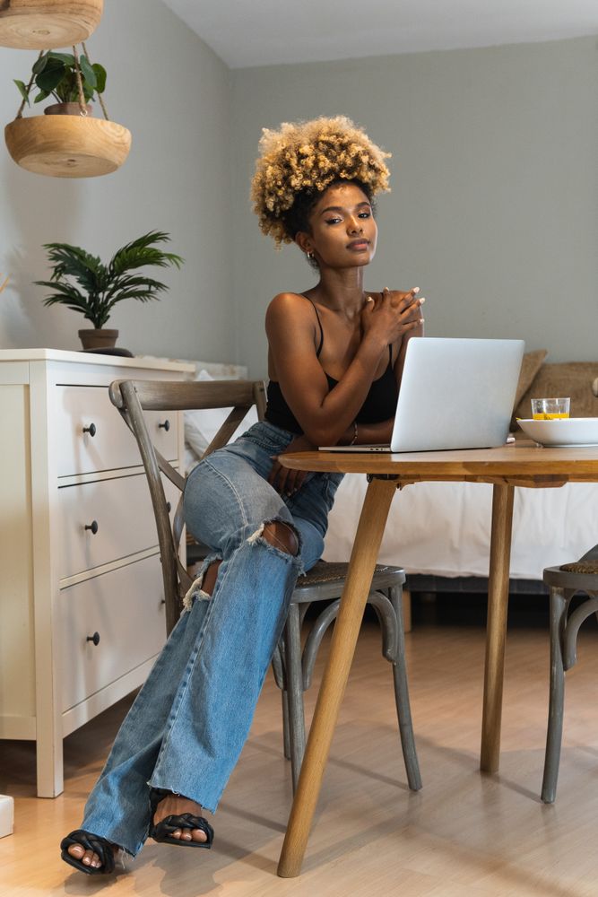Black woman with laptop sitting on chair during breakfast