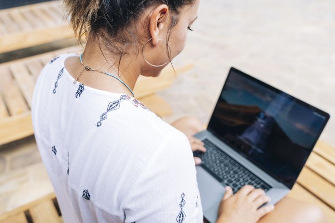 Relaxed woman using laptop while resting on deck chair