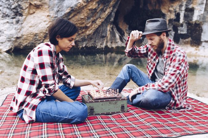 Casual couple playing chess on shore