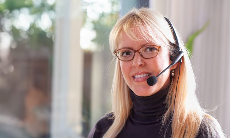Businesswoman Wearing Telephone Headset In An Office Setting.
