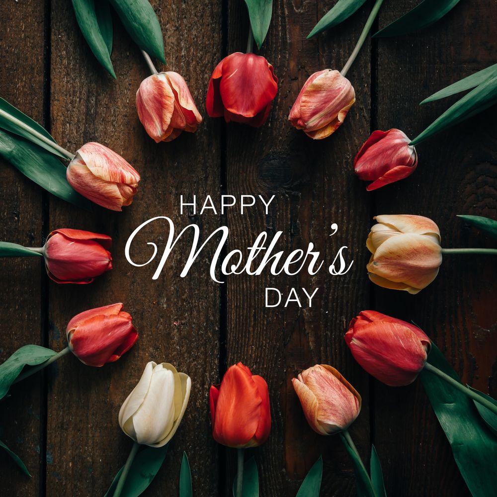 Circle of tulips on wooden background with “Happy Mother’s Day” text