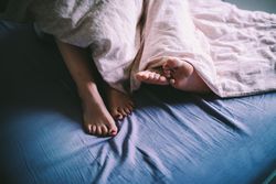 Two pairs of feet emerge from under the blankets