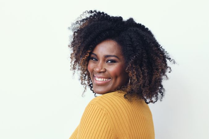 Studio shot of a happy Black woman in yellow shirt looking at camera