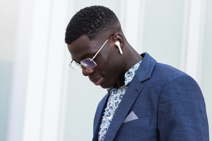Content Black businessman listening to music in earbuds in city