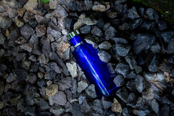 Blue perfume bottle mock up laying in rocks