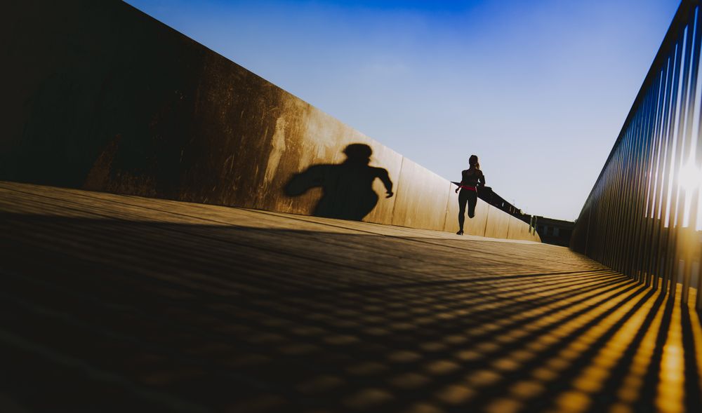 Woman running on walkway in sunny day with blue sky