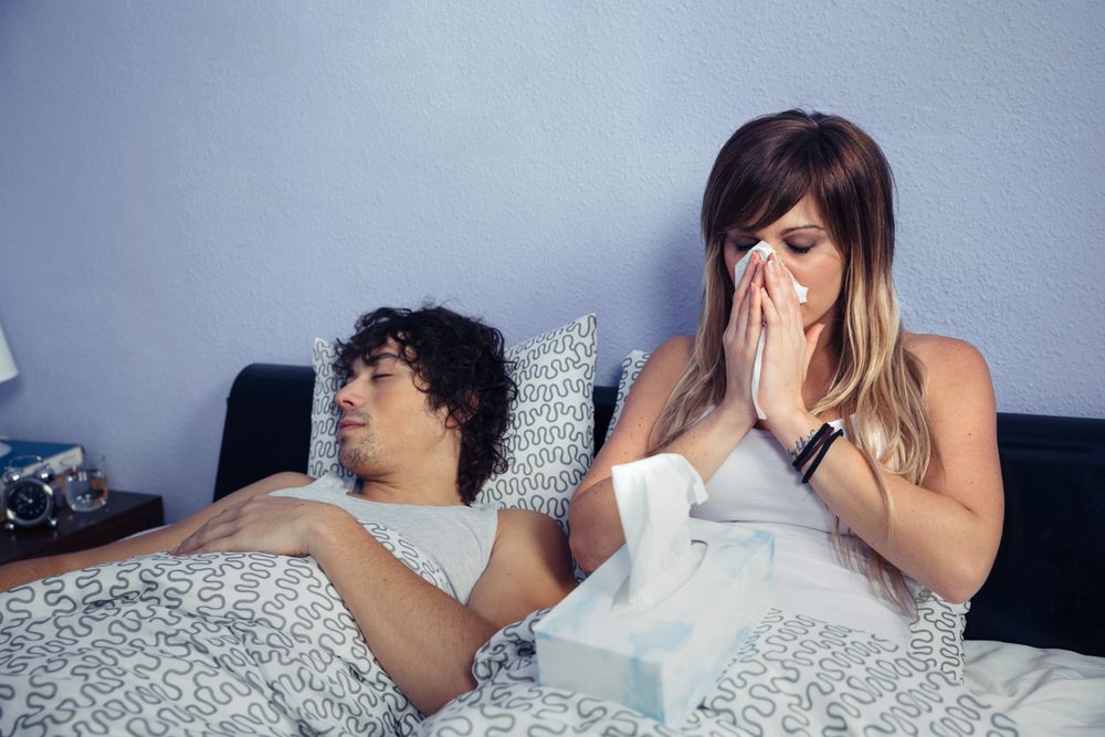 Sick woman sneezing and covering nose with tissue