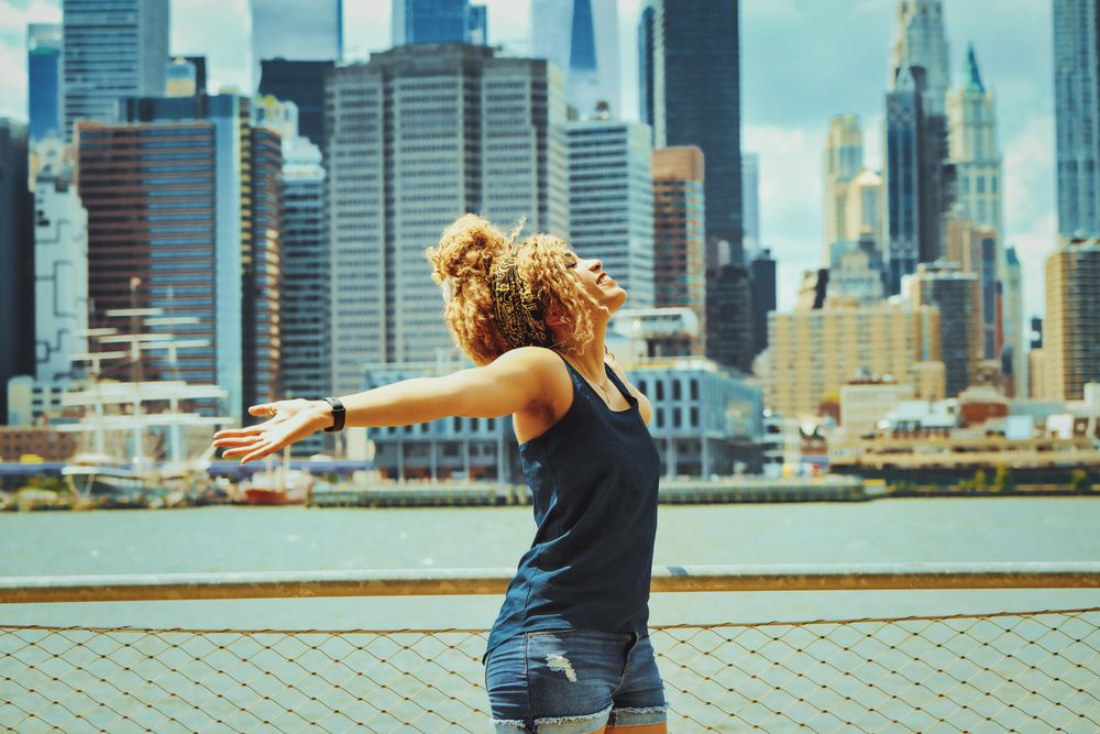 Black woman with her arms outstretched with Hudson River in the background, copy space