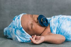 Newborn baby wrapped on soft blanket with pacifier