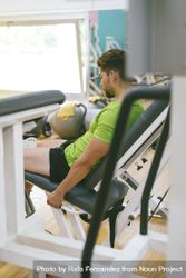 Looking through gym equipment at male in green t-shirt working out using machine, vertical 41ZELb