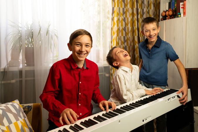 Smiling boys enjoying music while playing the piano together