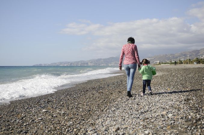 Woman and child walking on a rocky beach