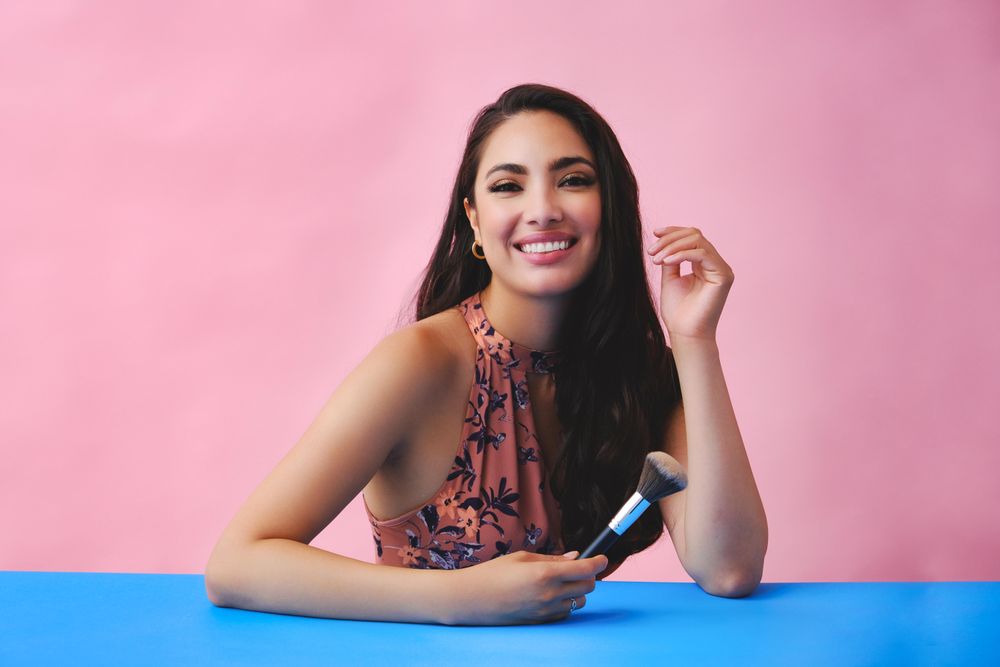 Elegant Hispanic woman with long brown hair holding large make up brush