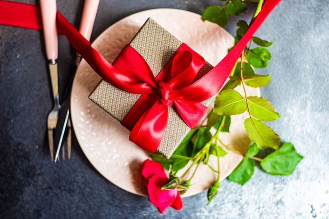 Top view of table setting with red rose and bow wrapped gift