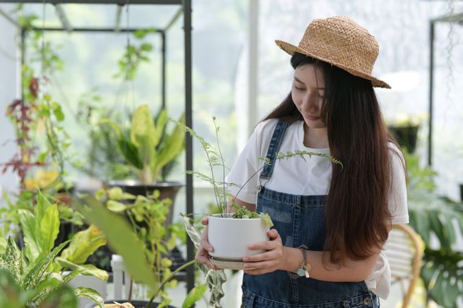 Asian woman working in a green house moving around a pot