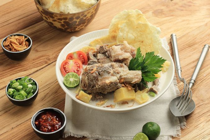 Soto betawi, bowl of Indonesian beef stew served with condiments