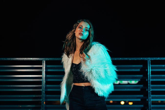 Female model on rooftop at night in faux fur coat