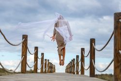 Woman with textile posing in air on footbridge